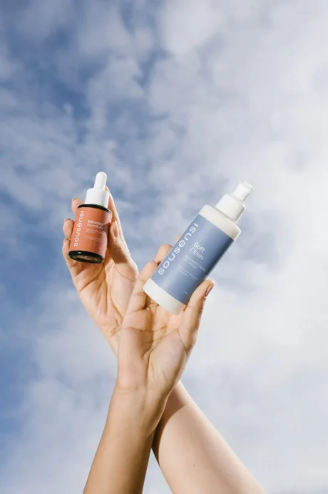 Mãos segurando o sérum de bakuchiol e o sabonete facial Soft Clean Sousènsi