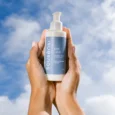 Mãos segurando o sabonete facial Soft Clean Sousènsi contra o céu azul