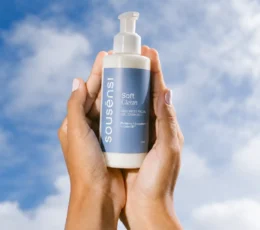 Mãos segurando o sabonete facial Soft Clean Sousènsi contra o céu azul