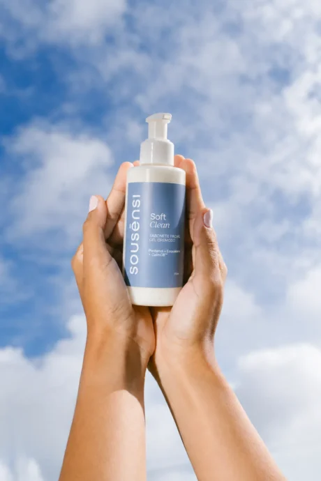 Mãos segurando o sabonete facial Soft Clean Sousènsi contra o céu azul
