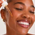Mulher sorrindo ao aplicar o sérum de bakuchiol Sousènsi